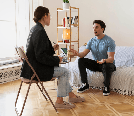 Man talking to therapist during individual therapy session, notes being taken.