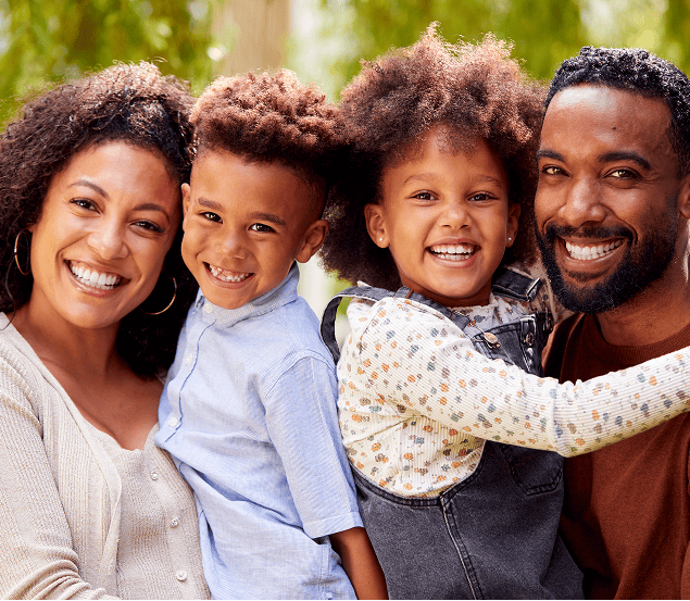 Happy family of four smiling. Vibe Psychiatry mental health clinic promotes family well-being.