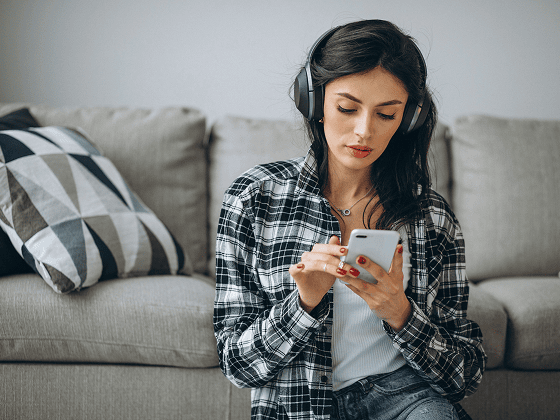 Woman with headphones using phone, possibly exploring mental health resources.