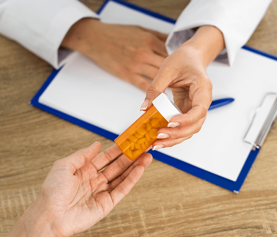 Doctor handing a bottle of pills to a patient, related to medication management psychiatry.