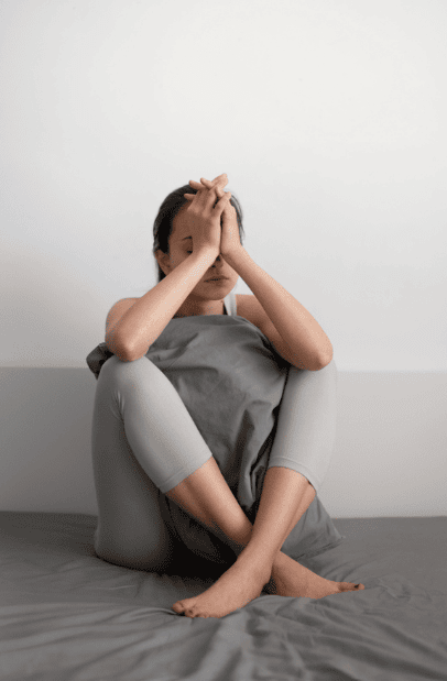 Sad woman hugging pillow, seeking depression treatment.